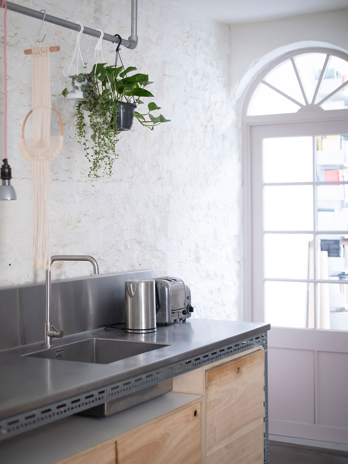Details such as the choice and arrangement of lighting and use of houseplants offer domestic concessions to help soften the space without disrupting the aesthetic.